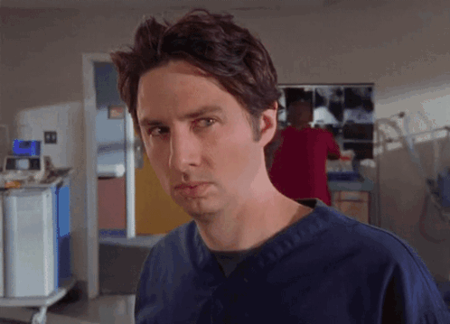 Man In Blue Scrubs Looking At Camera GIF