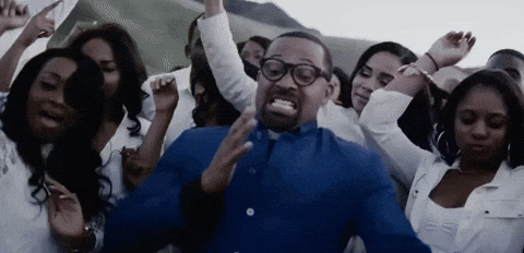Man In Blue Shirt And Glasses Surrounded By Crowd Of Women GIF