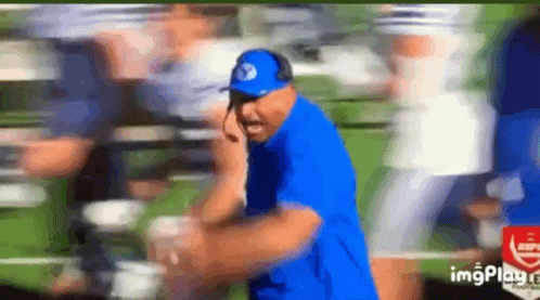 Man in Blue Shirt and Hat Talking on Cell Phone in Field
