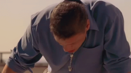 Man in Blue Shirt and Necklace Looking Down