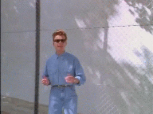 Man in Blue Shirt and Sunglasses at Fence