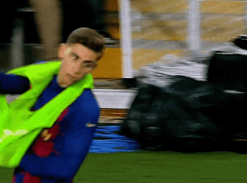Man In Blue Shirt And Yellow Vest Standing On Field GIF