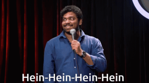 Man in Blue Shirt at Microphone Saying Hein-hein-hein