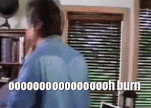 Man In Blue Shirt By Window With Blinds And Burn Sign GIF