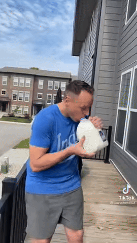 Man in Blue Shirt Drinking Milk from Pitcher