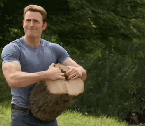 Man in Blue Shirt Holding Large Piece of Wood