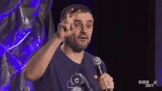 Man In Blue Shirt Holding Microphone Giving Peace Sign GIF