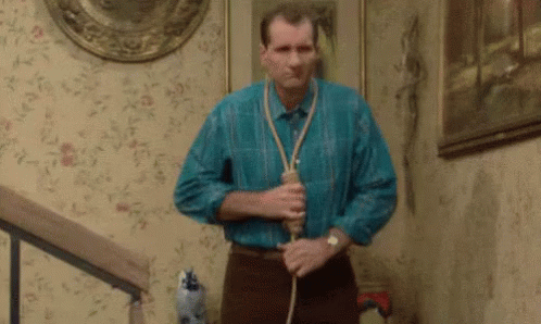 Man in Blue Shirt Holding Rope Around Neck on Stairs