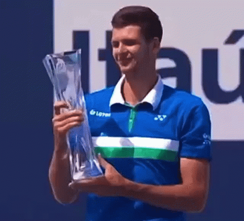 Man in Blue Shirt Holding Trophy and Smiling