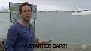 Man in Blue Shirt in Front of Starter Car Sign