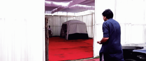 Man In Blue Shirt In Front Of Tent GIF