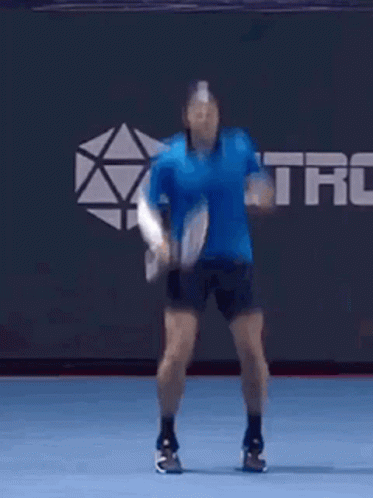 Man in Blue Shirt Jumping With Tennis Racquet