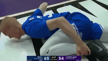 Man in Blue Shirt Laying on Ground During BYU vs Portland Wrestling Match