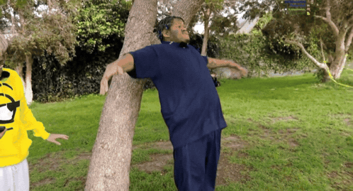 Man in Blue Shirt Leaning Against Tree