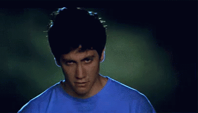 Man in Blue Shirt Making Funny Face in Dark Room