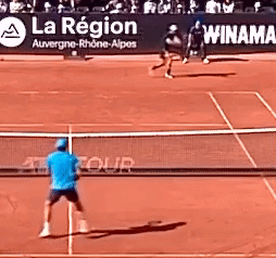Man in Blue Shirt Playing Tennis With La Region Sign