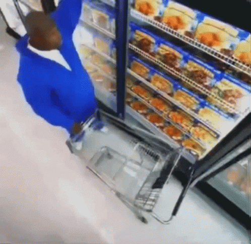 Man in Blue Shirt Pushing Shopping Cart in Store