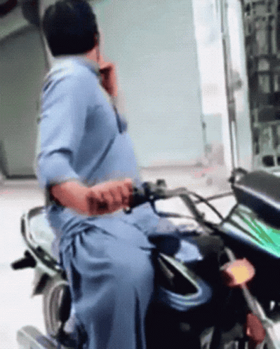 Man in Blue Shirt Riding Motorcycle Talking on Cell Phone