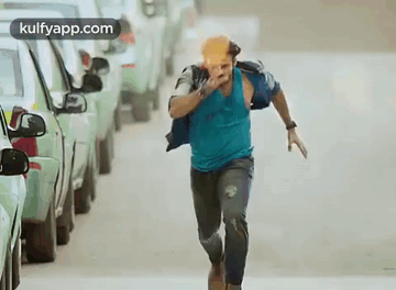Man in Blue Shirt Running with Bottle