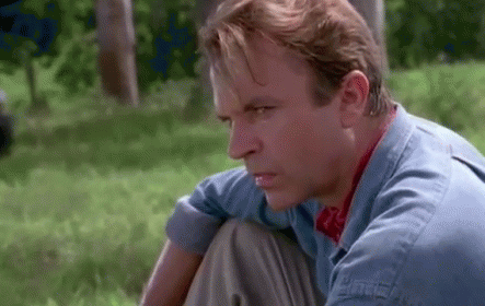 Man In Blue Shirt Sitting In Grass Looking GIF