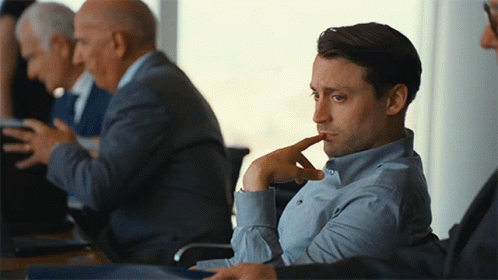Man In Blue Shirt Sitting With Hand On Chin GIF