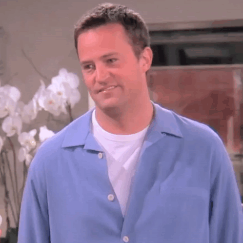 Man in Blue Shirt Smiling in Front of Flowers