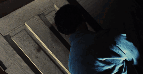 Man in Blue Shirt Standing in Dark Room