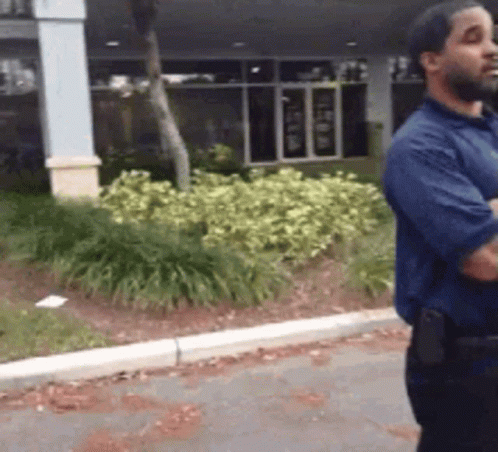 Man in Blue Shirt Standing on Sidewalk