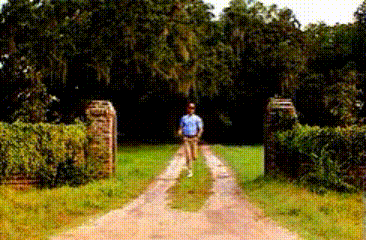 Man in Blue Shirt Walking Past Welcome Sign