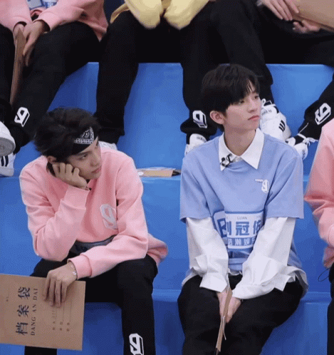 Man in Blue Shirt With 9 Next to Man in Pink Sweater