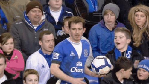 Man in Blue Shirt With Chan Holding Soccer Ball