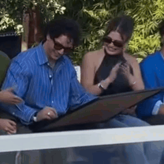 Man in Blue Striped Shirt Sitting Next to Woman with Sunglasses
