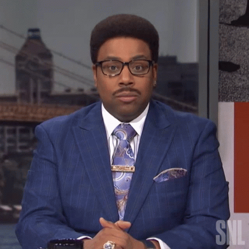 Man in Blue Suit and Tie Beside SNL Logo