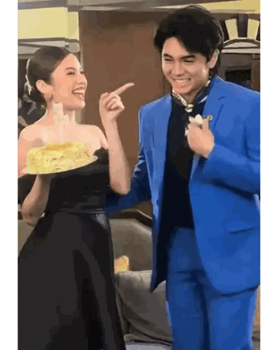 Man in Blue Suit and Woman in Black Dress Holding Cake