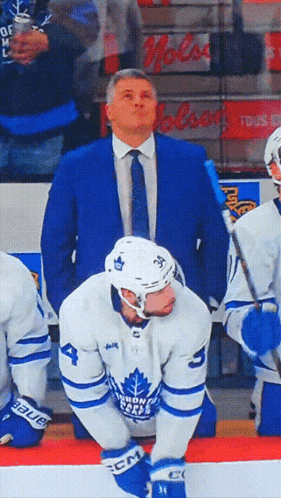 Man in Blue Suit Behind Toronto Maple Leafs Player
