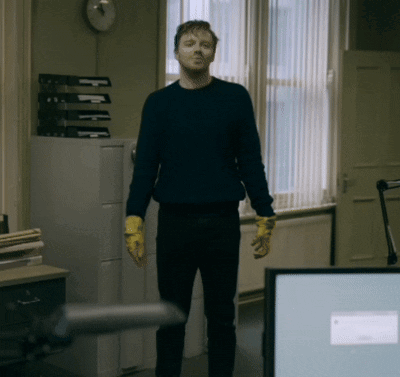 Man In Blue Sweater And Yellow Gloves By Window GIF