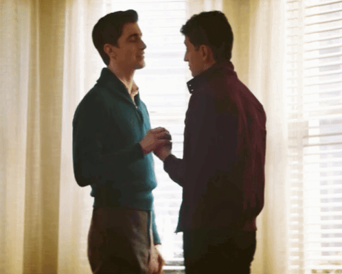 Man In Blue Sweater Holding Hand Of Man In Red Jacket GIF