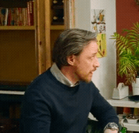 Man in Blue Sweater in Front of Bookcase