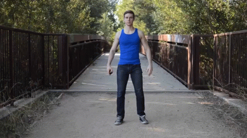 Man In Blue Tank Top Standing By Bridge GIF