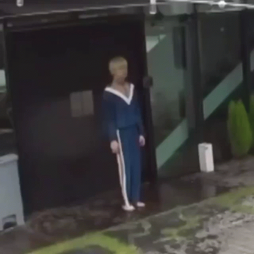 Man In Blue Tracksuit Holding Cane In Front Of Building GIF