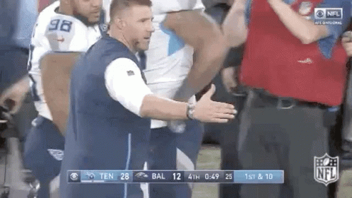 Man in Blue Vest in Front of Football Players