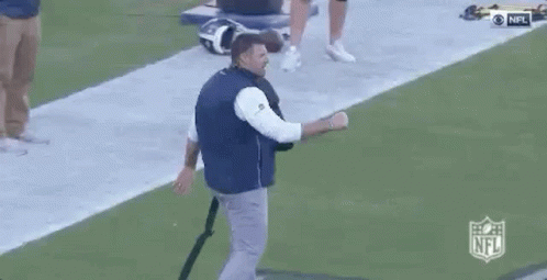 Man in Blue Vest Talking on Football Field