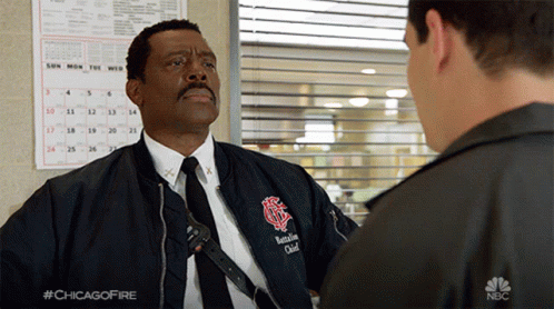 Man in Bomber Jacket and Tie Talks to Another Man in NBC Ad