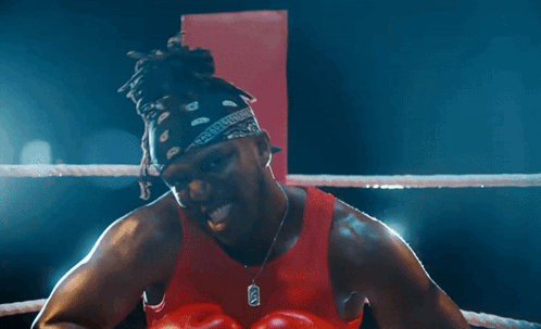 Man in Boxing Ring with Red Gloves and X Necklace