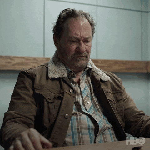 Man in Brown Jacket at Table With HBO Logo