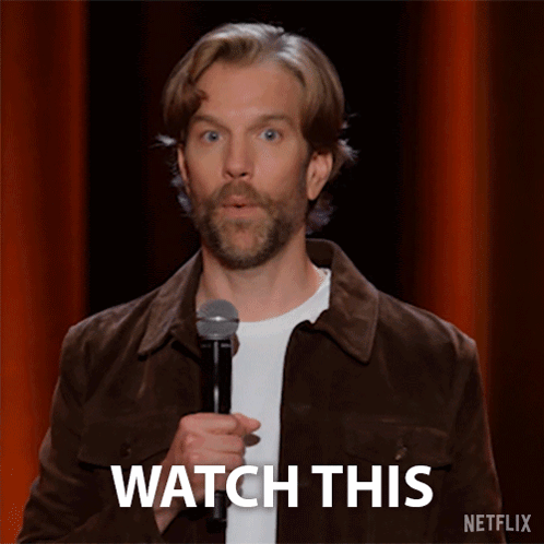 Man in Brown Jacket Holding Microphone Saying Watch This