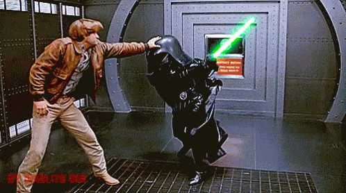 Man in Brown Jacket Next to Man with Green Lightsaber