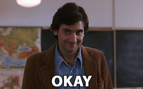Man in Brown Jacket Saying Okay in Classroom