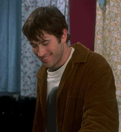 Man In Brown Jacket Smiling In Front Of Window GIF