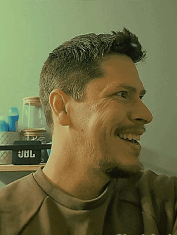 Man in Brown Shirt Smiling in Front of JBL Speaker